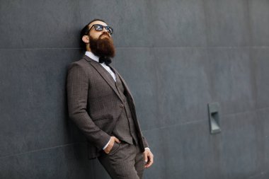 Modern iş adamı. Kendine güvenen genç adam açık havada cityscape arka plan ayakta iken uzak tam takım arıyor