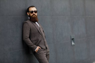 Modern iş adamı. Kendine güvenen genç adam açık havada cityscape arka plan ayakta iken uzak tam takım arıyor