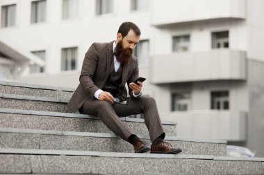 Yakışıklı bir genç işadamı telefonunu oturur iken adımlarla