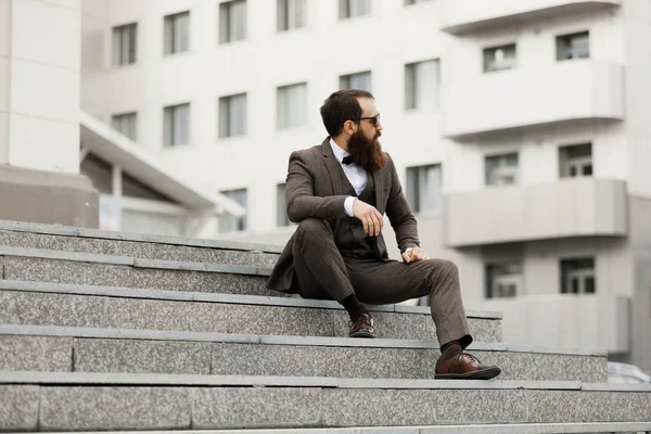 bearded man with a very interesting look with cityscape in the background