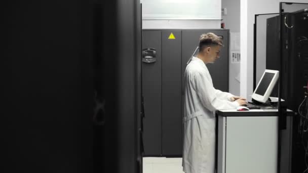 Técnico de TI Trabalha em um computador em Big Data Center cheio de servidores Rack. Ele executa diagnósticos e manutenção Stets up System . — Vídeo de Stock