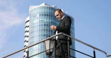 Adam sms manifatura app şehir iş bölgesinde akıllı telefon kullanma. Genç iş adamı mutlu giyen takım elbise ceket gülümseyen smartphone kullanarak