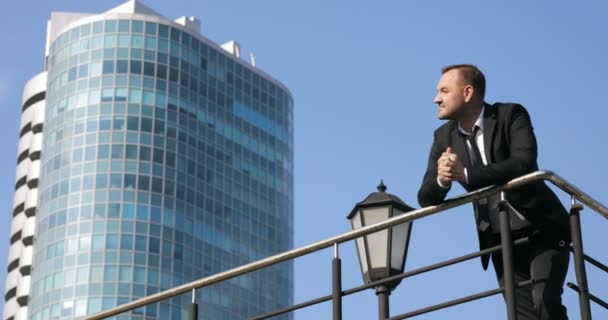 O empresário bem sucedido olha para a vista do horizonte da cidade durante o dia. Um homem no topo de um edifício olhando para a cidade — Vídeo de Stock