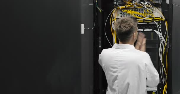 Engenheiro de servidor masculino caminha através do centro de dados de trabalho cheio de servidores de rack — Vídeo de Stock