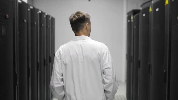 Engenheiro de servidor masculino caminha através do centro de dados de trabalho cheio de servidores de rack — Vídeo de Stock