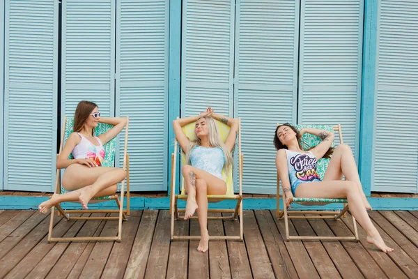 세 여자는 앉아 웃 고 밝은 배경에 해변에 일광욕 — 스톡 사진