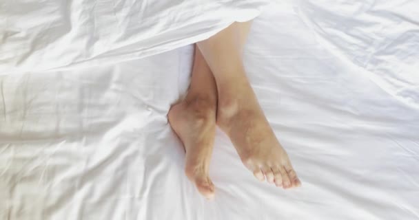 Female legs in bed view from above, white bedding, 4k — Stock Video