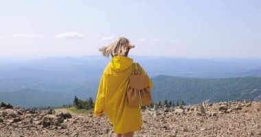 bir dağın tepesinde bir sarı yağmurluk kadında. Genç kadın sağlıklı aktif yaşam tarzı. Doğa macera.