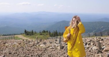 Uzun yürüyüşe çıkan kimse sırt çantası Hiking ile bir dağın tepesinde. kız bir dağın tepesinde bir sarı yağmurluk