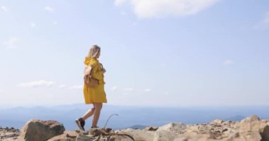 Uzun yürüyüşe çıkan kimse sırt çantası Hiking ile bir dağın tepesinde. kız bir dağın tepesinde bir sarı yağmurluk