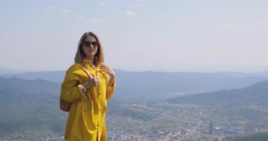 Uzun yürüyüşe çıkan kimse sırt çantası Hiking ile bir dağın tepesinde. kız bir dağın tepesinde bir sarı yağmurluk