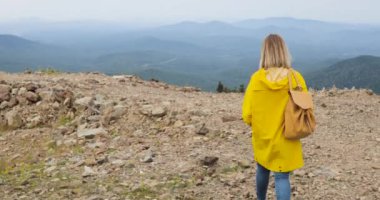 Etkin sağlıklı hipster dağlarda sarı yağmurluk hiking