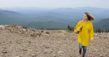 Sırt çantasında Dağları sarı yağmurluk ile yürüyen uzun yürüyüşe çıkan kimse kadın