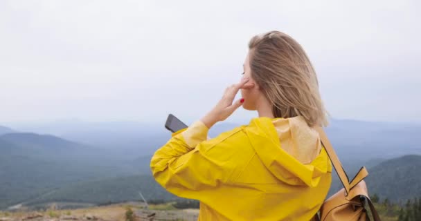 Жінка фотографує в горах зі смартфоном, фотографуючи мальовничий краєвид на природі, насолоджуючись подорожами у відпустці — стокове відео