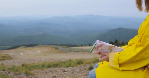 Joven mujer excursionista mirando el mapa desde la cima de la montaña — Vídeos de Stock