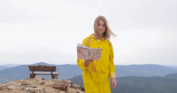 Joven mujer excursionista mirando el mapa desde la cima de la montaña — Vídeos de Stock