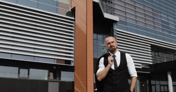 Feliz atractivo hombre de negocios caucásico caminando fuera cerca de gran edificio de oficinas y mirando a su alrededor . — Vídeos de Stock