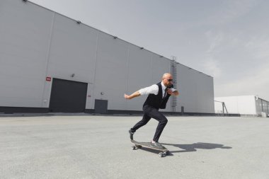 Kendine güvenen genç iş adamı iş uygun şehirde sokakta onun ofisine aceleyle longboard üzerinde
