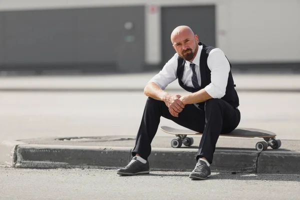 Elegáns üzletember ül longboard modern épület közelében — Stock Fotó