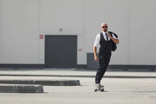 Jovem empresário confiante em terno de negócios em longboard apressando-se para seu escritório, na rua na cidade — Fotografia de Stock
