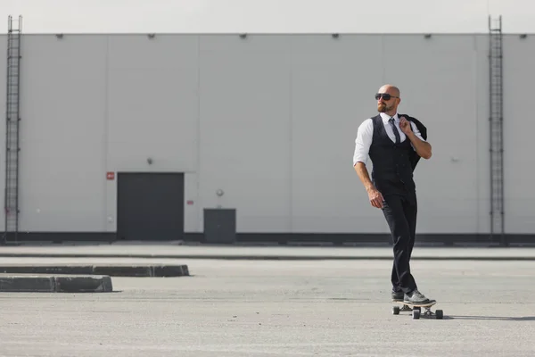 Jeune homme d'affaires confiant en costume d'affaires sur longboard se précipitant à son bureau, dans la rue dans la ville — Photo