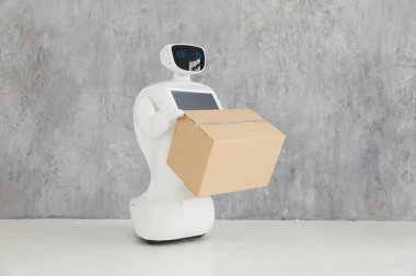 robot parsel sunar. teslimat kavramı. Özerk insansı robot karton kutunun içinde gri arka plan üzerinde el ile.