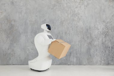 Özerk insansı robot karton kutunun içinde gri arka plan üzerinde el ile. robot parsel sunar. teslimat kavramı.