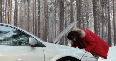 Araba motoru olarak görünen adam. adam tamir kırık araba. Kış sürüş, karlı köy yolunda sorun.