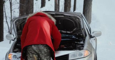 Araba motoru olarak görünen adam. adam tamir kırık araba. Kış sürüş, karlı köy yolunda sorun.