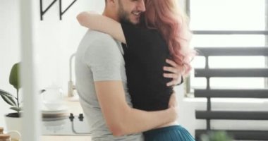 Güzel genç çift mutfakta sarılma. Mutlu erkek ve kadın konuşuyor, gülüyor ve öpüşme