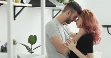 Mutlu erkek ve kadın konuşuyor, gülüyor ve öpüşme. Güzel genç çift mutfakta sarılma.