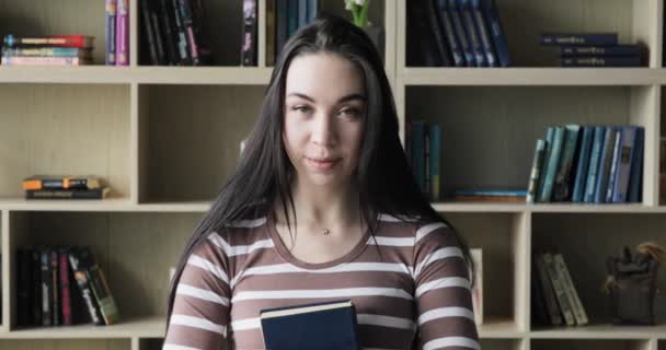 Primer plano retrato de joven bonita mujer sonriendo feliz mirando cámara en biblioteca librería fondo conocimiento aprendizaje — Vídeo de stock