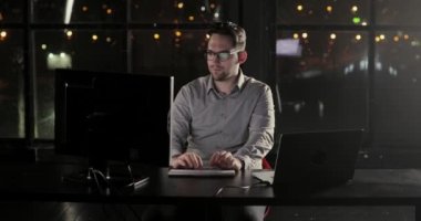Programcı adam ofiste gece geç saatlerde klavyede fazla mesai yazmaya çalışıyor.