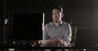 Programcı adam ofiste gece geç saatlerde klavyede fazla mesai yazmaya çalışıyor.