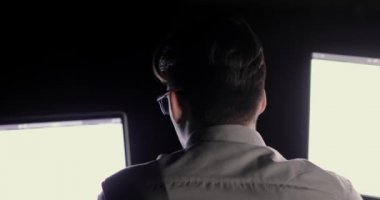 Programcı adam ofiste gece geç saatlere kadar iki monitörden önce oturan çalışıyor.