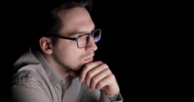 Adam karanlıkta ekrana bakıyor ve işyerinde oturan düşünme.