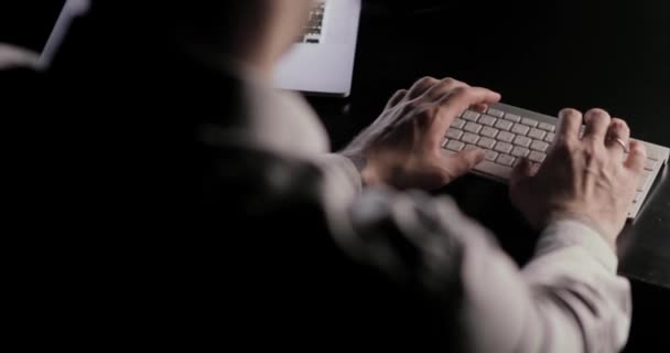 Manos de hombre escribiendo en el teclado sentado en la mesa en el lugar de trabajo . — Vídeo de stock