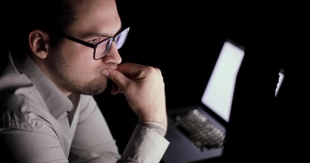 El hombre trabaja en la computadora, piensa y analiza los indicadores en la pantalla del monitor . — Vídeos de Stock