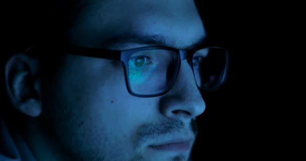 Reflektion av skärmen i mannens glasögon i mörkret. — Stockvideo