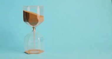 Mans el Mavi arka planda kum saati döner. Zaman ve geçis konsepti.