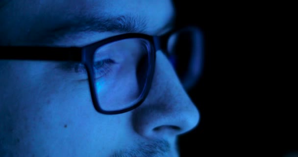 Reflektion av skärmen i mannens glasögon i mörkret. — Stockvideo