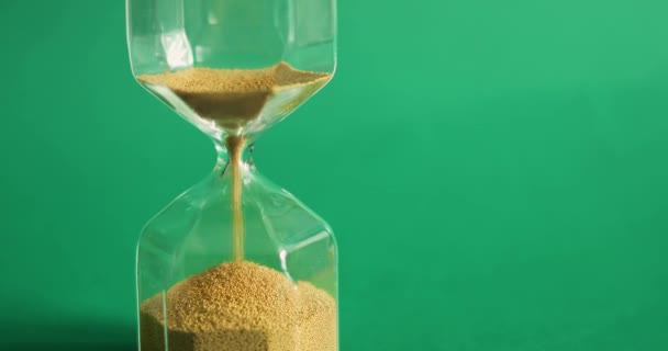 Sanduhr auf grünem Hintergrund. Die Zeit läuft ab. Zeit und Vergänglichkeit. — Stockvideo
