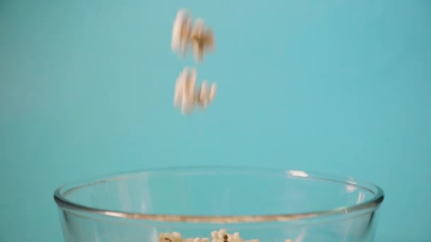 Palomitas de maíz se vierte en un recipiente transparente de vidrio sobre fondo azul . — Vídeo de stock