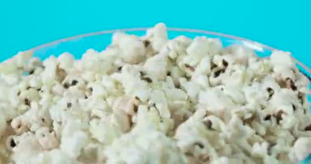 Mezza ciotola di vetro rotante con popcorn freschi su sfondo blu . — Video Stock