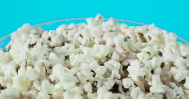 Teil einer rotierenden Glasschale mit frischem Popcorn auf blauem Hintergrund. — Stockvideo
