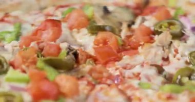 Pastırma ve sebzeler ile dönen lezzetli pizzanın yakın çekim görünümü.