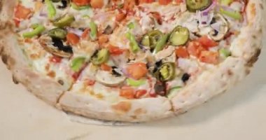 Açık ahşap arka planda domuz pastırması ve sebze ile dönen yarım lezzetli pizzanın yakın çekim görünümü.