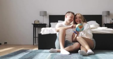 Yatak yanında oturan genç çift dünya balayı seyahat için bir yer seçiminde bakıyor. Aşk ilişki kavramı.