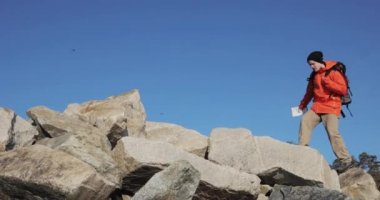 Genç adam turist tepenin üst taşları üzerinde yürüyüş ve etrafında bakıyor.