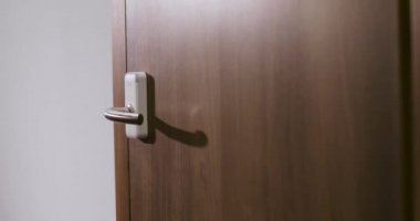 Adam otelin kapısına gelir ve elektronik anahtar kartını kullanarak odayı açar. El yakın çekim.